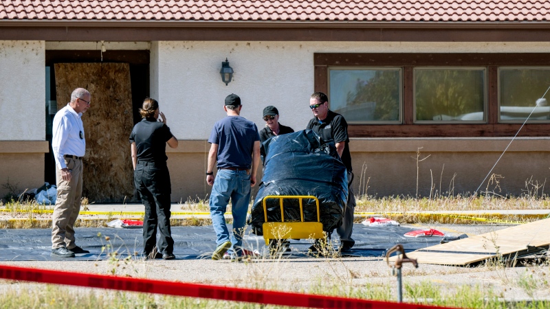 Fremont County coroner Randy Keller, left, and other authorities unload materials that will be used to put up tents at the Return to Nature Funeral Home on Oct. 7, 2023, in Penrose, Colo.  (Parker Seibold / The Gazette via AP)
