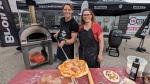 Will Aiello and Emily Richards make pizzas in an outdoor oven.