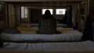 A man sits on a shelter bed on March 21, 2024. (Jenny Kane / The Associated Press)