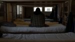 A man sits on a shelter bed on March 21, 2024. (Jenny Kane / The Associated Press)