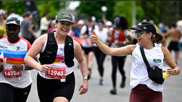 A runner is cheered on by a friend as they enter the final stretch of the half marathon of the Ottawa Race Weekend in Ottawa, on Sunday, May 26, 2024. THE CANADIAN PRESS/Justin Tang