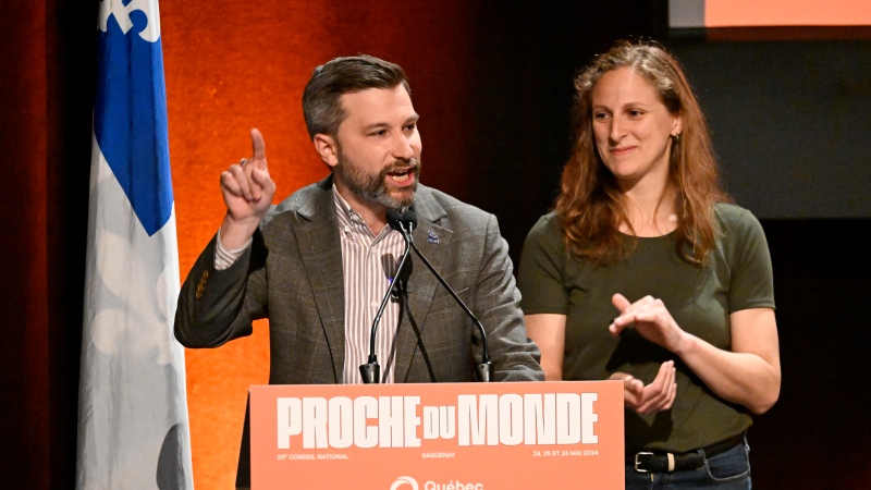 Quebec Solidaire co-spokesperson Gabriel Nadeau-Dubois, left, speaks to delegates at the beginning Quebec Solidaire national council meeting, Saturday, May 25, 2024 in Saguenay as co-spokesperson Christine Labrie, right, applauds. THE CANADIAN PRESS/Jacques Boissinot