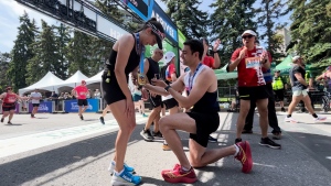 Andrew Dupuis getting down on one knee to propose to his girlfriend, Austyn Roseborough at the finish line after the marathon during Ottawa Race Weekend on May 26, 2024. (Jackie Perez/CTV News Ottawa)