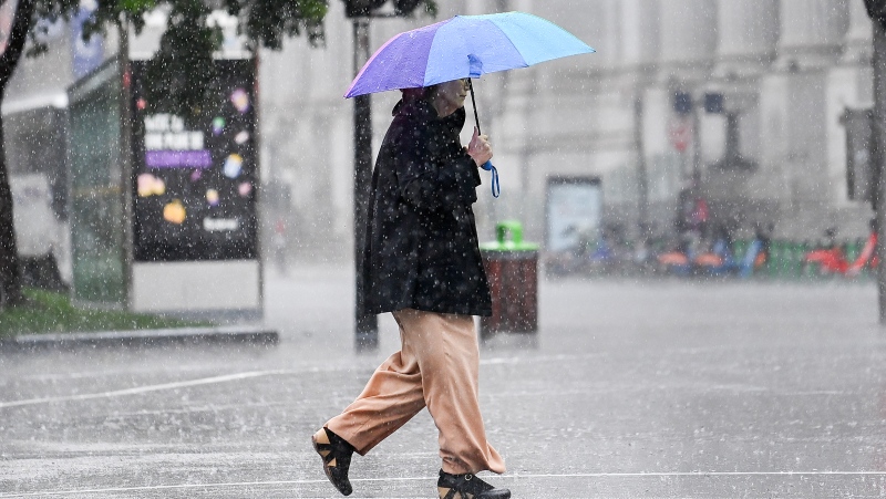A person walks along a street during heavy rain in Montreal, Saturday, October 7, 2023. (Graham Hughes/The Canadian Press)
