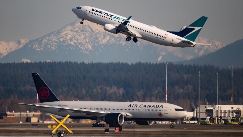 An Air Canada flight departing for Toronto, bottom, taxis to a runway as a Westjet flight bound for Palm Springs takes off at Vancouver International Airport, in Richmond, B.C., on Friday, March 20, 2020. THE CANADIAN PRESS/Darryl Dyck