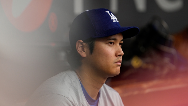 Los Angeles Dodgers' Shohei Ohtani sits in the dugout during the eighth inning of a baseball game against the Cincinnati Reds, Sunday, May 26, 2024, in Cincinnati. (AP Photo/Jeff Dean)