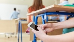 A student uses a cellphone in a classroom in this undated stock image. (Shutterstock)