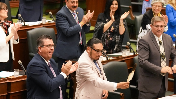NDP MPP Sol Mamakwa brandishes an eagle feather towards the government benches as he stands in the Ontario Legislature in Toronto, on Tuesday, May 28, 2024, to speak in his language, Oji-Cree, the first time in history that Indigenous language is used in the provincial legislature to ask a question of the government. THE CANADIAN PRESS/Chris Young
