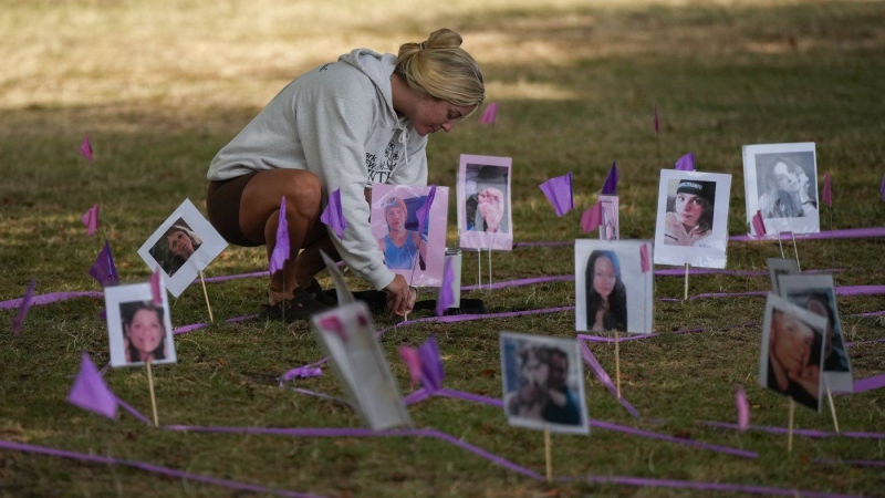 Taylor Snider adjusts a photograph of an overdose victim as members of Moms Stop the Harm mark International Overdose Awareness Day in Vancouver, on Thursday, Aug. 31, 2023. (THE CANADIAN PRESS/Darryl Dyck)