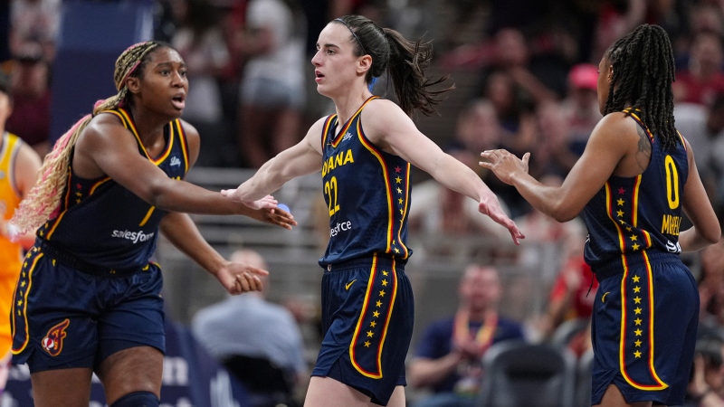 Indiana Fever guard Caitlin Clark (22) is congratulated by Aliyah Boston (7) and Kelsey Mitchell (0) during their WNBA game against the Los Angeles Sparks on May 28, 2024. (Michael Conroy/AP Photo)