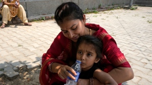 A woman gives drinking water to her child as she waits under the shade of a tree in New Delhi, India. (Manish Swarup/AP Photo)