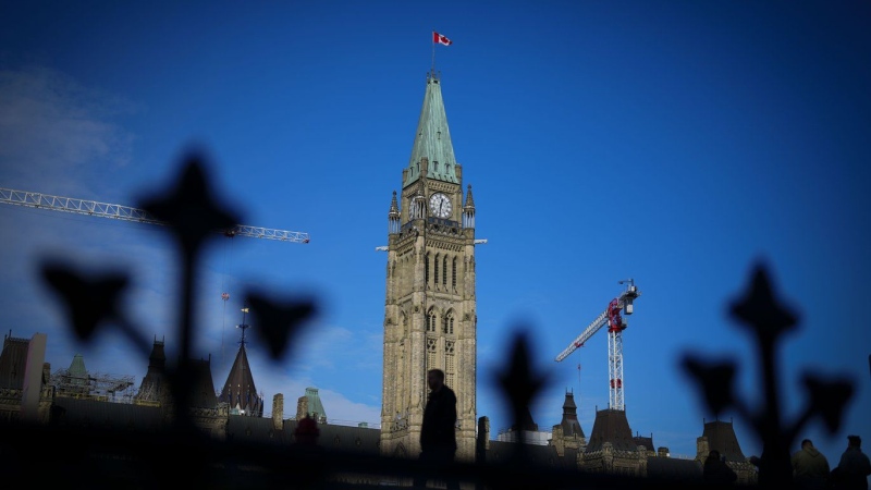 A person makes their way past the Peace Tower on Parliament Hill in Ottawa on Tuesday, Feb. 13, 2024. (Sean Kilpatrick/The Canadian Press)