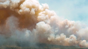 In this aerial image, an aircraft, center, flies near a wildfire burning near Barrington Lake in Shelburne County, Nova Scotia, on Wednesday, May 31, 2023. (Source: Communications Nova Scotia/The Canadian Press via AP)