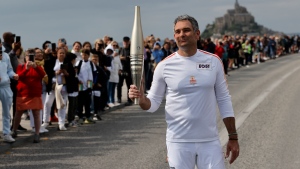 Maxime Gohier holds the Olympic torch in front of the Mont-Saint-Michel on Friday, May 31, 2024 in Brittany. (Jeremias Gonzalez / AP Photo)