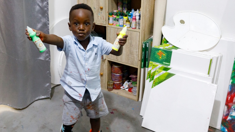 Ace-Liam Nana Sam Ankrah, who will turn two in July, shows off his paint tubes at his mother's art gallery in Accra, Ghana, Monday, May 27, 2024. (Misper Apawu / AP Photo)