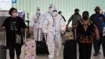 Air China flight crew members in hazmat suits walk through the arrivals area at Los Angeles International Airport in Los Angeles, Tuesday, Nov. 30, 2021.
