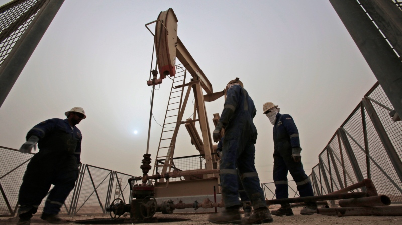 FILE - In this Jan. 8, 2015 file photo, men work on an oil pump during a sandstorm in the desert oil fields of Sakhir, Bahrain. (AP Photo/Hasan Jamali, File)