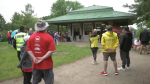 Participants and volunteers for the 2024 Kitchener-Waterloo Gutsy walk stand in the rain to hear this year's fundraising total. June 2, 2024. (Shelby Knox/CTV News)