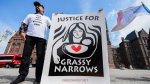 A demonstrator holds a sign following a press conference announcing intention to litigate against the Government over contamination of Grassy Narrows, in Toronto on Tuesday, June 4, 2024. THE CANADIAN PRESS/Christopher Katsarov