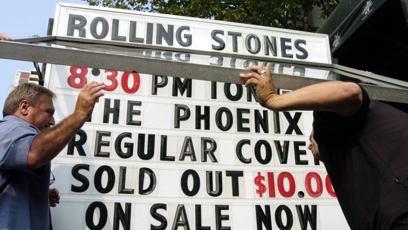 Unidentified men add the words 'sold out' to the billboard in front of the Phoenix Concert Theatre in Toronto on Wednesday August 10, 2005. (CP PHOTO/Aaron Harris)