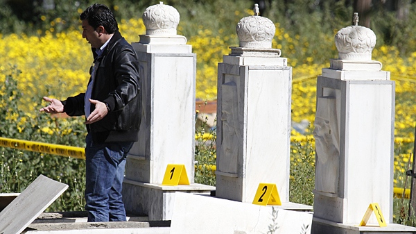 A police officer reacts as he stands near the graves of two Cyprus Archbishops at a cemetery in capital Nicosia, Cyprus, Sunday, March 21, 2010. (AP / Petros Karadjias)
