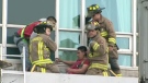 Firefighters assist the dazed window washer as he sits on the ledge of a Front Street condominium on Friday, April 2, 2010.