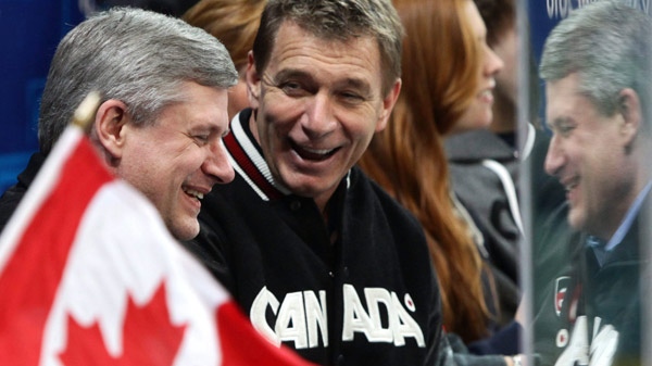 Prime Minister Stephen Harper sits with Rick Hansen as Canada plays Norway during first period bronze medal ice sledge hockey action at the 2010 Winter Paralympics in Vancouver, Friday, March 19, 2010. (Darryl Dyck / THE CANADIAN PRESS)        