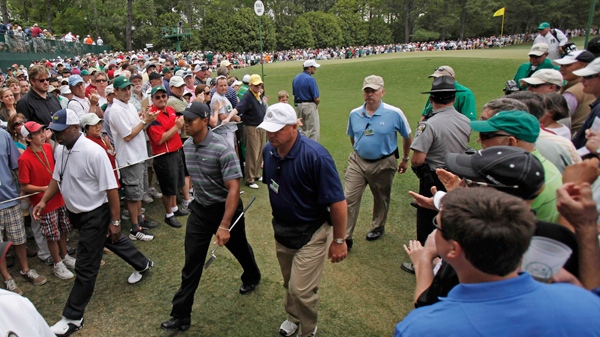 Escorted by security personnel, Tiger Woods walks to the second tee during the first round of the Masters golf tournament in Augusta, Ga., Thursday, April 8, 2010. (AP / Rob Carr)