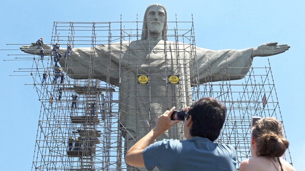 Tourists take photographs of the statue of Christ the Redeemer surrounded by scaffolding in Rio de Janeiro on March 9, 2010. (AP / Felipe Dana)