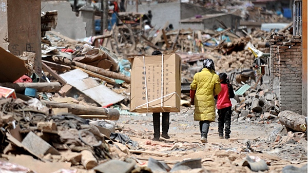 A family brings relief supplies to home in quake-hit Yushu County, northwest China's Qinghai Province, Sunday, April 18, 2010. (AP / Xinhua, Nie Jianjiang)