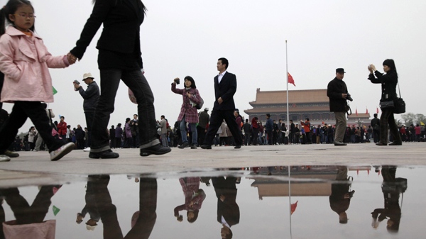 Visitors walk past a puddle of water which reflects a Chinese national flag flying at half-staff on Tiananmen Square in Beijing, China, Wednesday, April 21, 2010. China ordered all flags be flown at half-staff and called a halt to all entertainment, including online games and sports events, for the national day of mourning. (AP / Ng Han Guan)