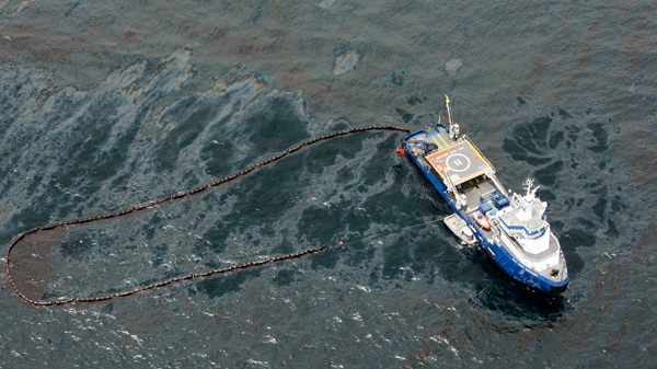 In this aerial photo taken in the Gulf of Mexico, a boat with an oil boom tries to contain oil spilled from the explosion and collapse of the Deepwater Horizon oil rig, on Friday, April 23, 2010. (AP / Gerald Herbert)