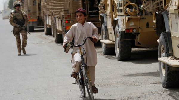 An Afghan boy rides a bicycle past British armoured vehicles in Lashkar Gah, Helmand province, south of Kabul, Afghanistan, May 1, 2010. (AP / Dar Yasin)