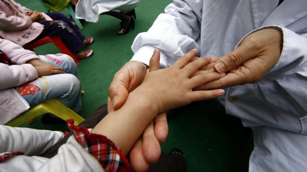 Two doctors check children in a kindergarten for symptoms of hand, foot and mouth disease in Suining in southwest China's Sichuan province Friday March 27, 2009. (AP Photo) 