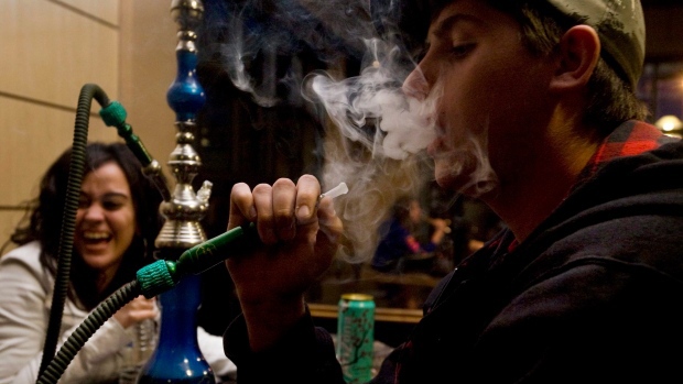 Gene Beaver, 19, right, blows a trail of smoke while enjoying a hookah with friends Christina Tsionas, 18, left, and Aminah Rawdah, 18, at the Alexandria Cafe in Scarborough, Ont. Saturday, May 8, 2010. (THE CANADIAN  PRESS/Darren Calabrese)