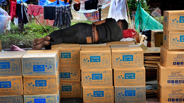 An anti-government protester sleeps on boxes of drinking water at the "Red Shirt" encampment on Wednesday, May 12, 2010, in Bangkok, Thailand. The Thai government turned to siege tactics Wednesday after fruitless efforts to compromise with protesters barricaded in central Bangkok, announcing that the army would limit supplies of water, food and electricity to the protest zone. (AP / Wong Maye-E)