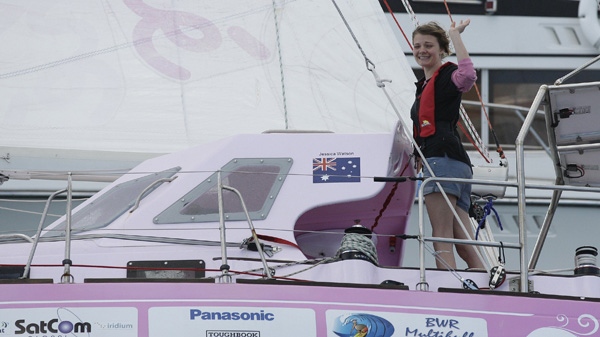 Jessica Watson, 16 ans, fait signe de la main alors qu'elle franchit la ligne d'arrivée à l'entrée du port de Sydney à Sydney, en Australie, le samedi 15 mai 2010. (AP / Rob Griffith)