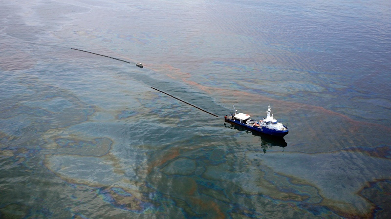 A boat hauling a boom makes its way through oily waters near the site of the Deepwater Horizon oil leak in the Gulf of Mexico, Wednesday, May 19, 2010. (AP / Press-Register, G.M. Andrews)
