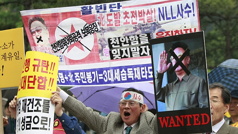 South Korean protesters, holding with defaced portraits of North Korean leader Kim Jong Il, shout slogans during a rally against North Korea in Seoul, South Korea, Tuesday, May 25, 2010. (AP Photo/Ahn Young-joon)
