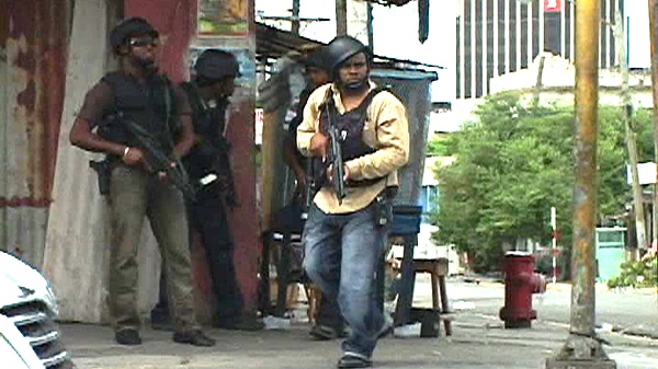 This image from APTN video shows armed plainclothes police at a street corner in Kingston, Jamaica Tuesday May 25, 2010. (AP / APTN)