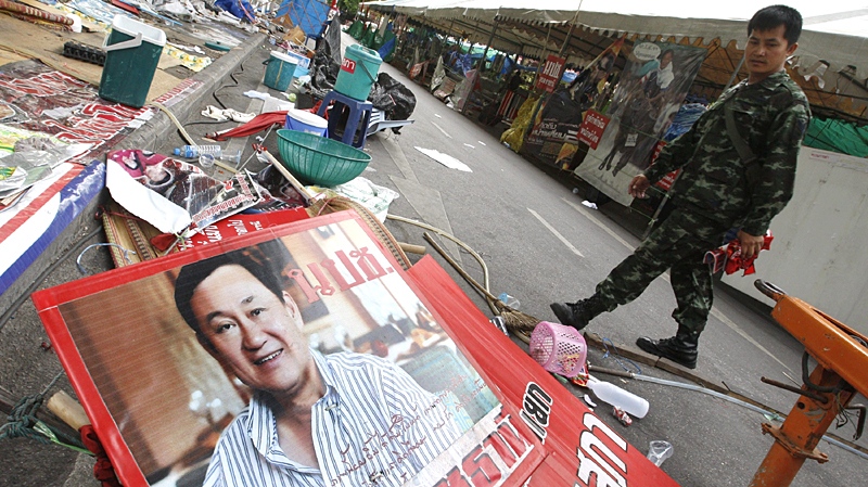 A Thai soldier walks by a poster of ousted Prime Minister Thaksin Shinawatra left behind by anti-government protesters in Bangkok, Thailand, Friday, May 21, 2010. (AP Photo/Sakchai Lalit)