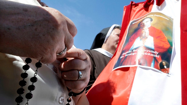 A woman holds a rosary next to a portrait of Father Jerzy Popieluszko during a beatification mass for him in Warsaw, Poland, Sunday June 6, 2010. (AP / Alik Keplicz)