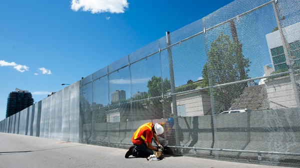 A construction worker puts up a three metre high steel security fence outside the Toronto Metro Convention Centre for the upcoming Toronto G20 summit in Toronto on Tuesday, June 8, 2010. (THE CANADIAN PRESS / Nathan Denette)
