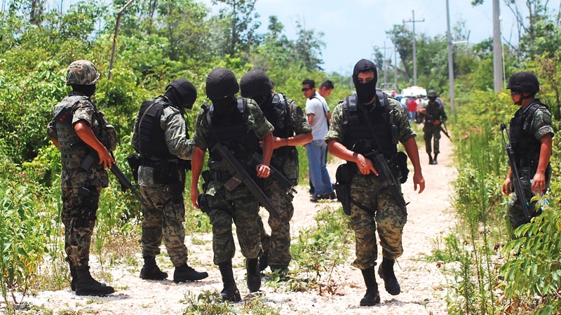 Mexican Army soldiers secure a dirt road after bodies were found nearby in several sinkholes in the resort city of Cancun, Mexico Friday June 18, 2010. (AP / Israel Leal)