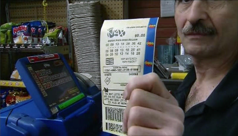 A convenience store owner holds up a Lotto Max ticket in Toronto, Friday, June 18, 2010.