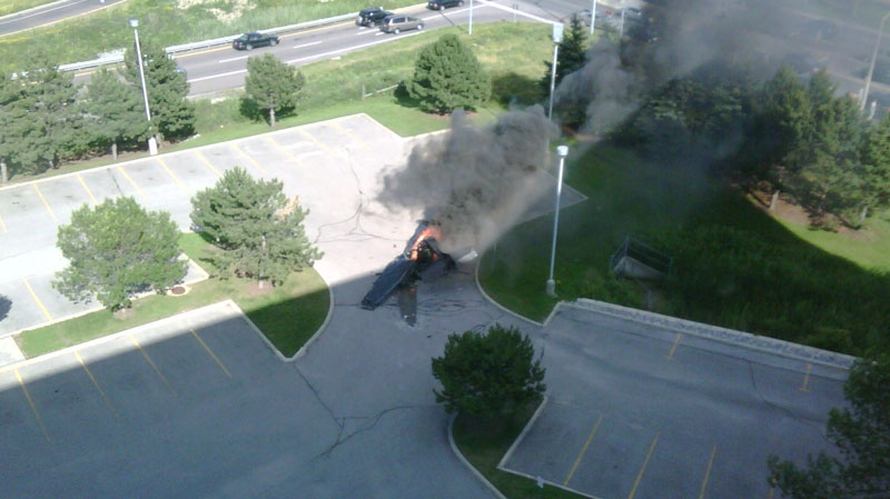 The smoking remains of a plane are seen near the Buttonville Airport on Sunday, June 20, 2010. The photo was taken by witness Amit Kohli, who was working on the eighth floor of a nearby office building at the time of the crash.