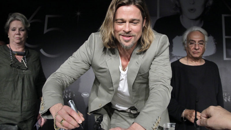 Actor Brad Pitt, centre signs an autograph during a press conference for Killing Them Softly at the 65th international film festival, in Cannes, southern France, Tuesday, May 22, 2012. 