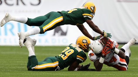 Edmonton Eskimos' Lawrence Gordon, top, and Chris Thompson, 29, prevent B.C. Lions' Emmanuel Arceneaux, right, from catching the ball during first half pre-season CFL action in Vancouver, B.C., on Sunday June 20, 2010. THE CANADIAN PRESS/Darryl Dyck