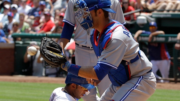 Toronto Blue Jays catcher J.P. Arencibia, foreground, reaches out for the throw as Texas Rangers' Elvis Andrus, centre, scores on a sacrifice fly-out by Adrian Beltre in the first inning of a baseball game in Arlington, Texas, on Saturday, May 26, 2012. (AP / Tony Gutierrez)