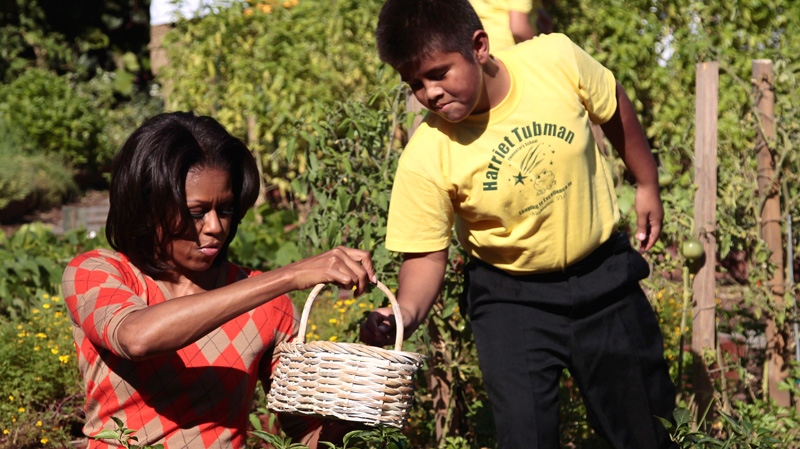 First lady Michelle Obama gets help from fifth grade student Sterling Zapata in filling a basket with peppers in the White House garden in Washington, Oct. 5, 2011. (AP / Pablo Martinez Monsivais)